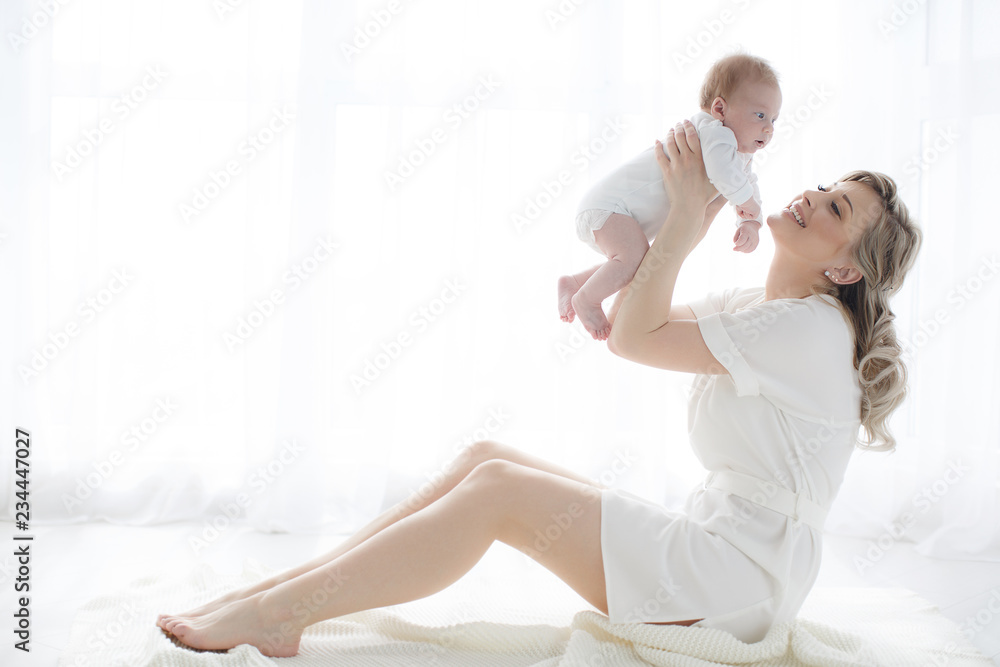 Young mother holding her newborn child.Woman and new born boy relax in a white bedroom.A young mother gently holds her newborn son in her arms.Family at home.Young mother playing whith her newborn son Young mother holding her newborn child.Woman and new born boy relax in a white bedroom.A young mother gently holds her newborn son in her arms.Family at home.Young mother playing whith her newborn son