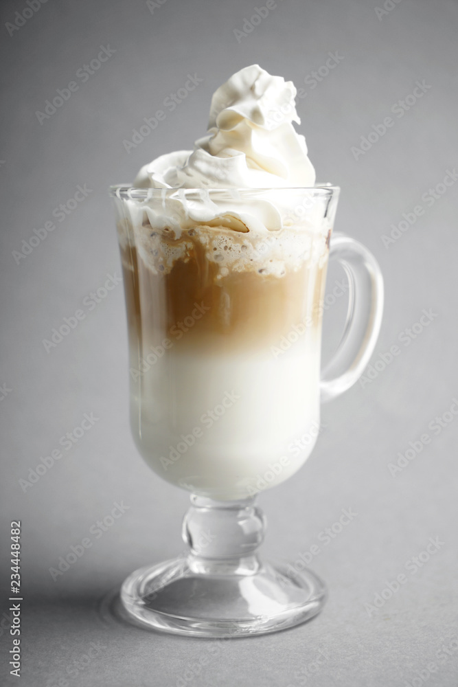 Cold coffee covered with whipped cream in glass on grey background Cold coffee covered with whipped cream in glass on grey background