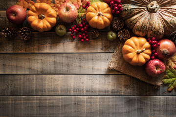 Top view of  Autumn maple leaves with Pumpkin and red berries on old wooden background. Thanksgiving day concept.