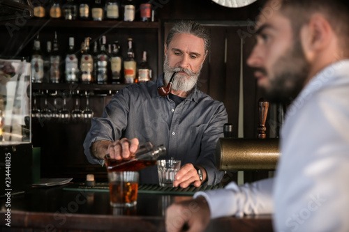 Senior barman serving clien...