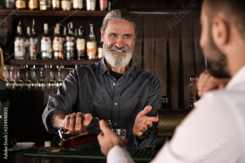 Senior barman serving client in pub