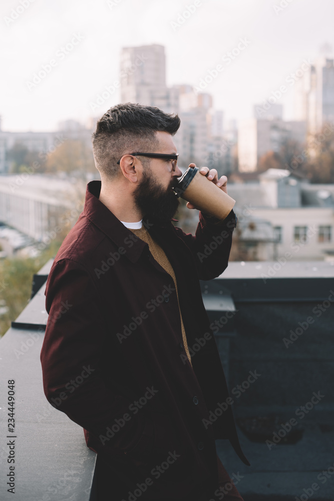 stylish adult man in glasses holding coffee to go on rooftop stylish adult man in glasses holding coffee to go on rooftop