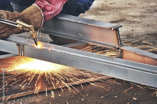 Steel cutting with acetylene torch, industrial worker on site construction.