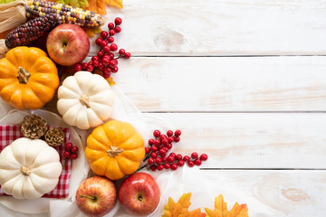 Top view of  Autumn maple leaves with Pumpkin and red berries on white wooden background. Thanksgiving day concept.