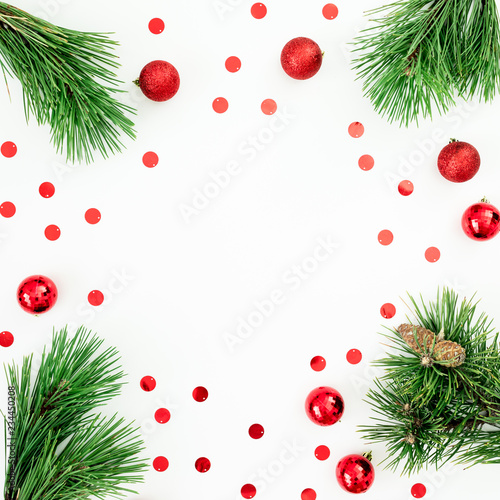 Christmas frame made of pine branches and red balls decoration with confetti on white background. Festive background. Flat lay, top view