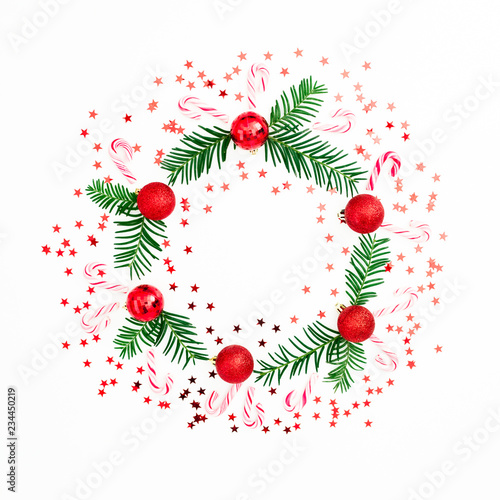 Fototapeta Naklejka Na Ścianę i Meble -  Christmas frame made of fir branches and red balls decoration with confetti on white background. Festive background. Flat lay, top view