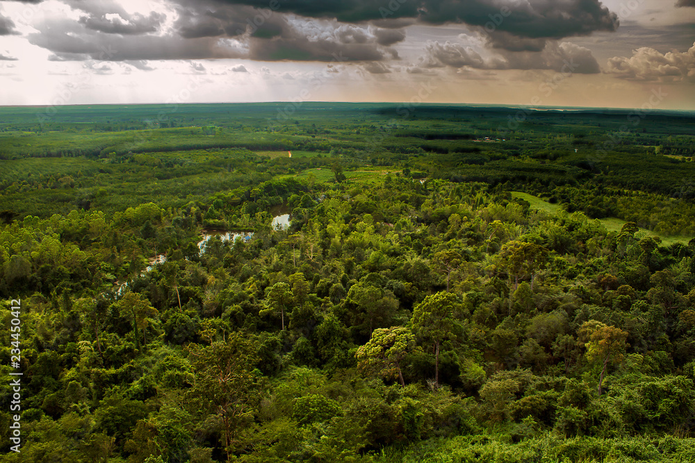 Looking off the mountains edge as a storm rolls in with dark clouds and shadows starting to cover the forest and farm lands surrounding Phu Sing, Bueng Kan Province, Thailand.