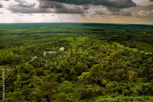 Obraz na płótnie Looking off the mountains edge as a storm rolls in with dark clouds and shadows starting to cover the forest and farm lands surrounding Phu Sing, Bueng Kan Province, Thailand. w salonie
