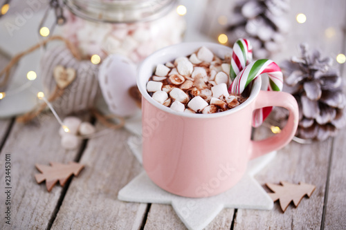 A pink mug full of cocoa with marshmallows on a rustic background