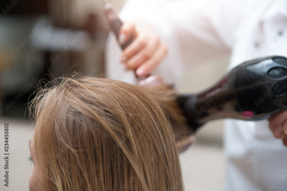 Naklejka premium Close up of woman and hairdresser with a hairdryer