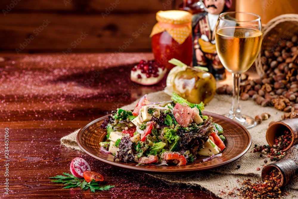 vegetable salad with tomatoes, cheese and bell peppers on a brown plate and a glass of white wine on a dark wooden background. beautiful composition. Georgian cuisine. close-up vegetable salad with tomatoes, cheese and bell peppers on a brown plate and a glass of white wine on a dark wooden background. beautiful composition. Georgian cuisine. close-up