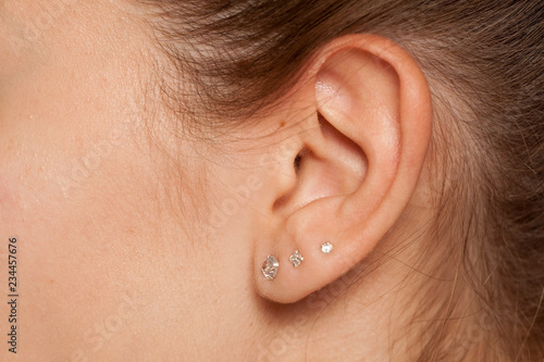 Fotografija Closeup of female ear with three earrings