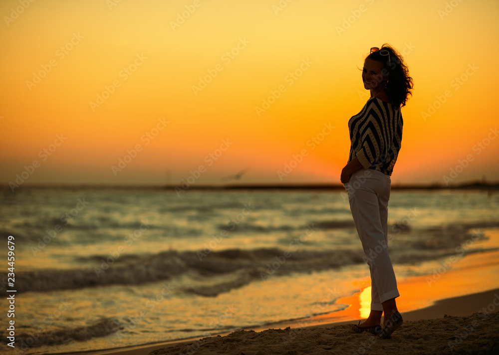 Full length portrait of modern woman on seashore in evening