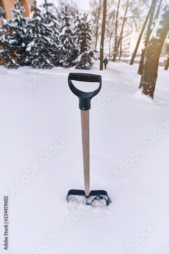 Shovel stuck in the snow after a storm. Shovel item for blizzard survival. Snow and ice remova equipment. Cleaning the snow with a shovel. Preparing for the winter photo