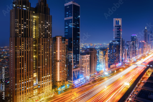 Beautiful aerial view to Dubai downtown city center lights skyline at night, United Arab Emirates. Long exposure light trails effect