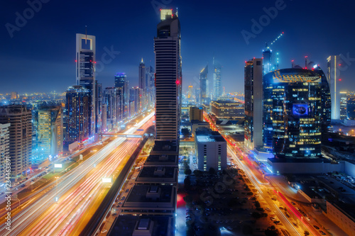 Beautiful aerial view to Dubai downtown city center lights skyline at night, United Arab Emirates. Long exposure light trails effect photo