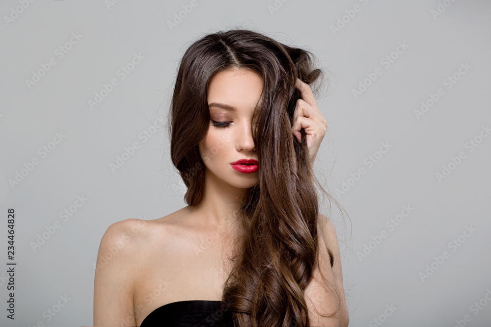 Fashion woman with curly shiny long hair. Gray background Fashion woman with curly shiny long hair. Gray background