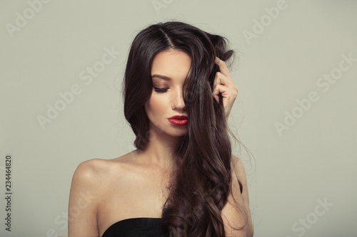 Fashion woman with curly shiny long hair. Gray background