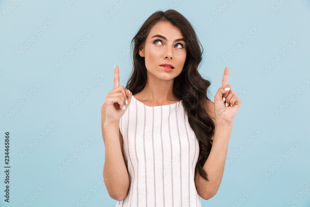Thinking young woman posing isolated over blue background wall pointing. Thinking young woman posing isolated over blue background wall pointing.