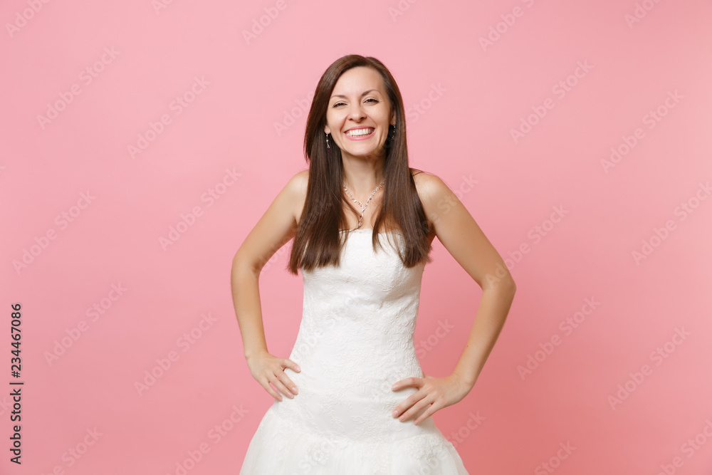Portrait of joyful smiling bride woman in beautiful white wedding lace dress standing with arms akimbo isolated on pink pastel background. Wedding celebration concept. Copy space for advertisement. Portrait of joyful smiling bride woman in beautiful white wedding lace dress standing with arms akimbo isolated on pink pastel background. Wedding celebration concept. Copy space for advertisement.