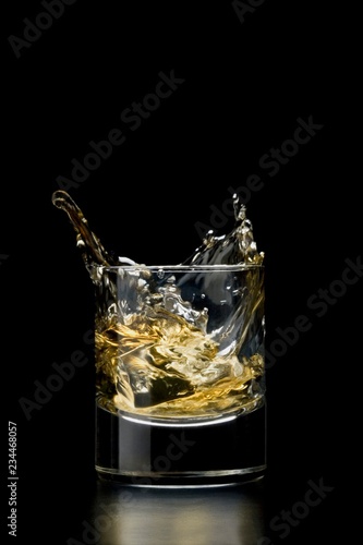 Ice cube falling into glass of whisky photo