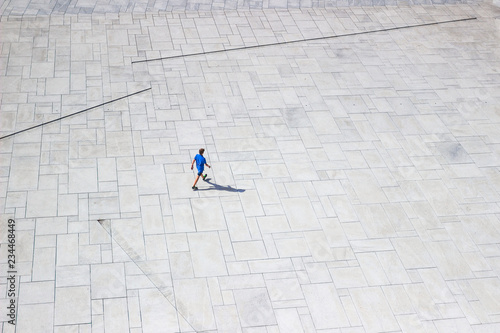 OSLO, NORWAY - AUG 10, 2016. Downright view at a lonely man walking like ant on white pavement near Oslo Opera House. View from the roof of Opera in sunny summer day. Isolated man on white background