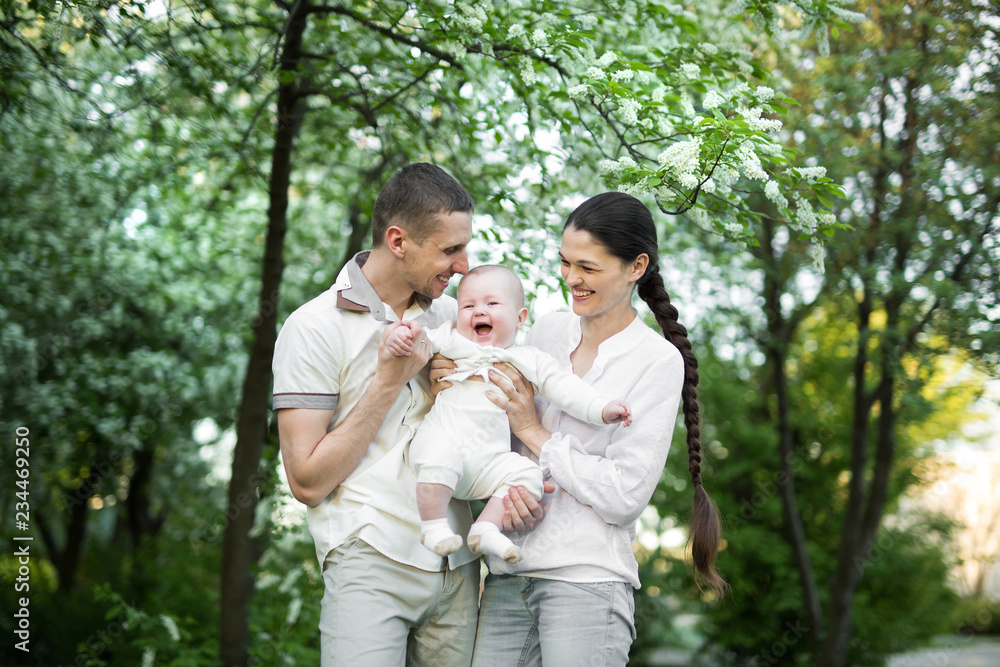 Portrait of a young family with a child. Happy young family spending time outdoor on a summer day. Happiness and harmony in family life. Happy family concept. Portrait of a young family with a child. Happy young family spending time outdoor on a summer day. Happiness and harmony in family life. Happy family concept.