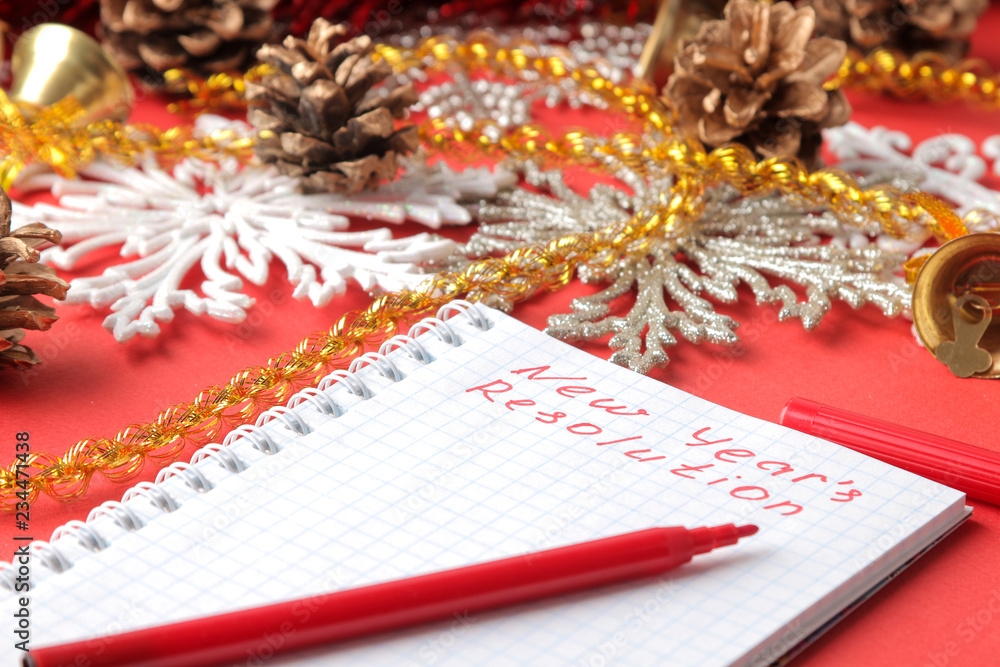 inscriptions New Year's resolution in a notebook and various New Year's decorations on a red background. New Year Christmas. holidays inscriptions New Year's resolution in a notebook and various New Year's decorations on a red background. New Year Christmas. holidays