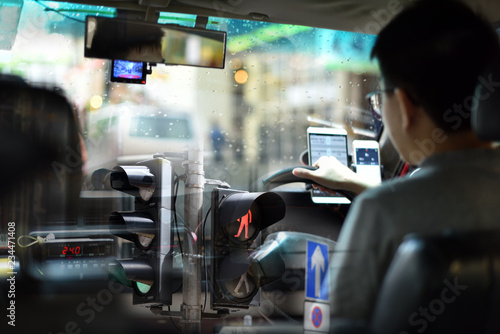Canvas Print An energetic superimposed or double exposure of a Hong Kong taxi driver on his duty, looking from passenger back seats and a traffic light pole and street sign from a Hong Kong main street