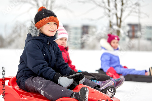 childhood, sledging and season concept - group of happy little kids sliding on sleds in winter photo