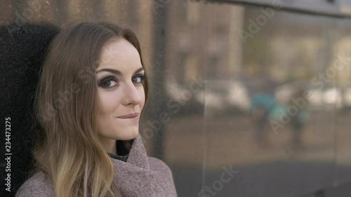 Beautiful fashionable blonde woman with gorgeous makeup in blush jacket slyly looking into camera move eyebrow. Close up slow motion portrait.