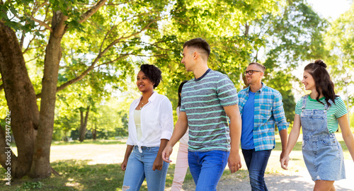 people, friendship and international concept - group of happy friends walking in park