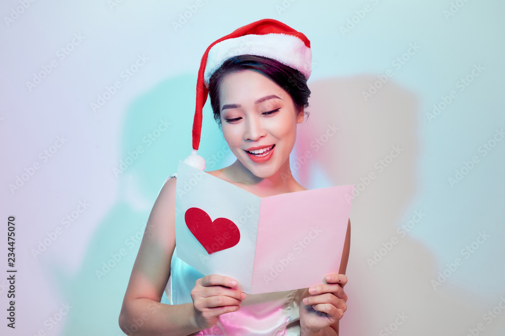 beautiful young woman holding a valentine postcard with a pink heart on light background beautiful young woman holding a valentine postcard with a pink heart on light background
