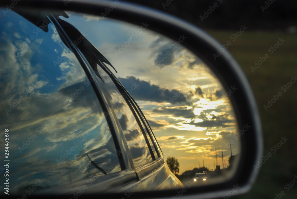Sunset is reflected in the rearview mirror of a car Sunset is reflected in the rearview mirror of a car