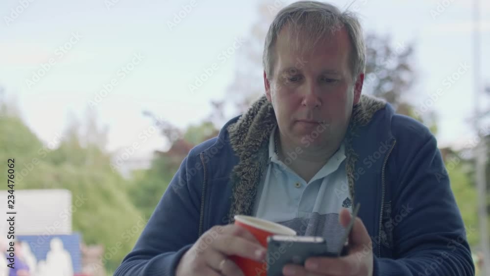 Mature man messages someone on his smartphone sitting at table Mature man messages someone on his smartphone sitting at table
