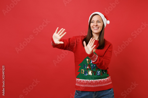 Joyful Santa girl touch something like push click on button, pointing at floating virtual screen isolated on red background. Happy New Year 2019 celebration holiday party concept. Mock up copy space.