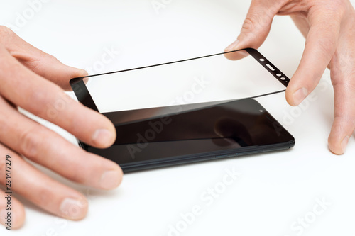 A man is holding a protective glass for a smartphone. photo