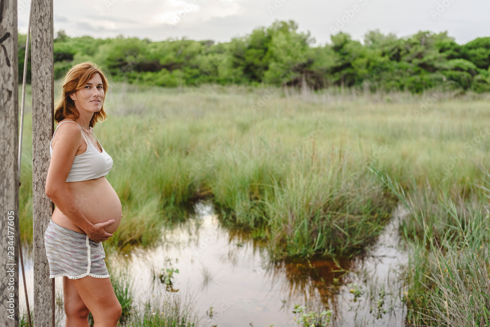 Pregnant woman relaxing looking at the landscape of a lake.