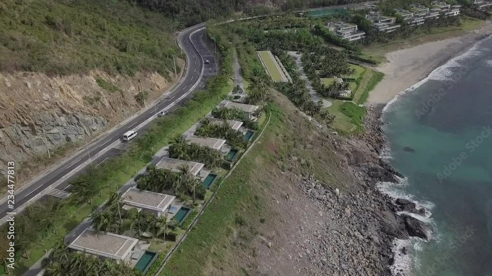 2K Aerial view of beautiful Vietnamese landscape with curvy mountain road in the coastal seaside with the lonely beach and luxurious villas. Cam Ranh, Vietnam. White van is driving. 2K Aerial view of beautiful Vietnamese landscape with curvy mountain road in the coastal seaside with the lonely beach and luxurious villas. Cam Ranh, Vietnam. White van is driving.
