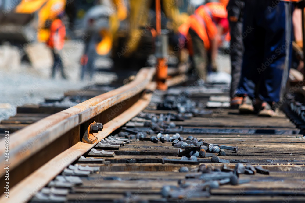 Workers in bright uniforms lay railway or tram tracks Workers in bright uniforms lay railway or tram tracks