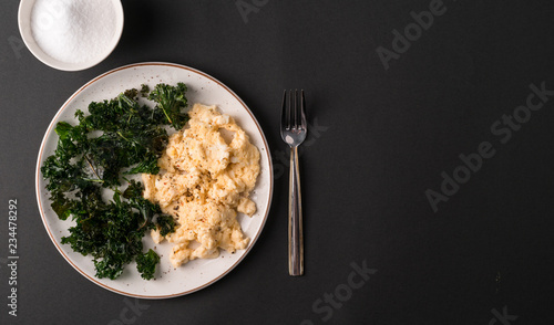 a breakfast of kale and scrambled eggs on a dark backdrop