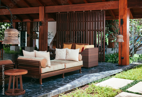 Resort style couch, wood table with fabric cusion and pillow under wooden pavilion photo