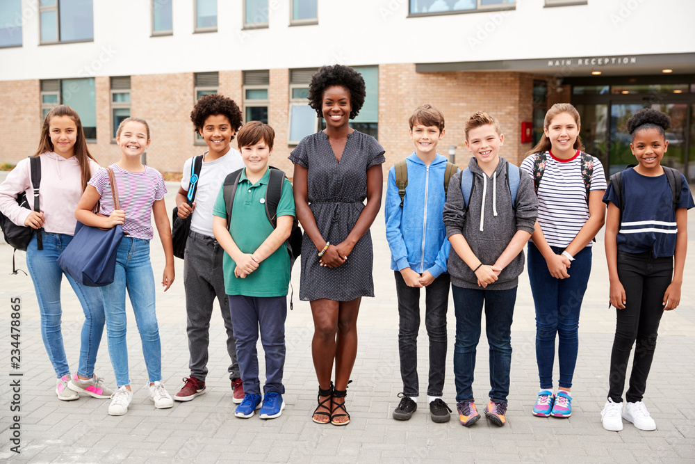 Obraz premium Portrait Of Smiling High School Student Group With Female Teacher Standing Outside School Buildings