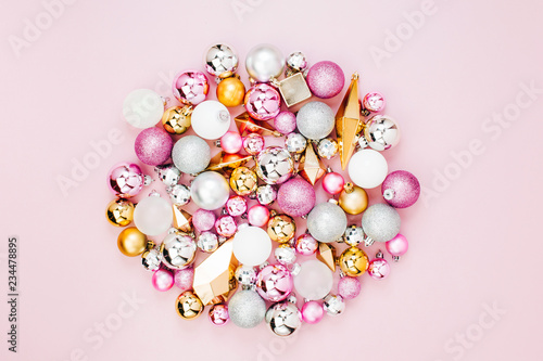 Holiday round arrangement with Stylish Christmas shiny balls and gold crystals on pastel pink background. Flat lay, top view