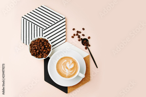 Breakfast with a cup of coffee with a geometric decor on pale pink background. Flat lay, top view