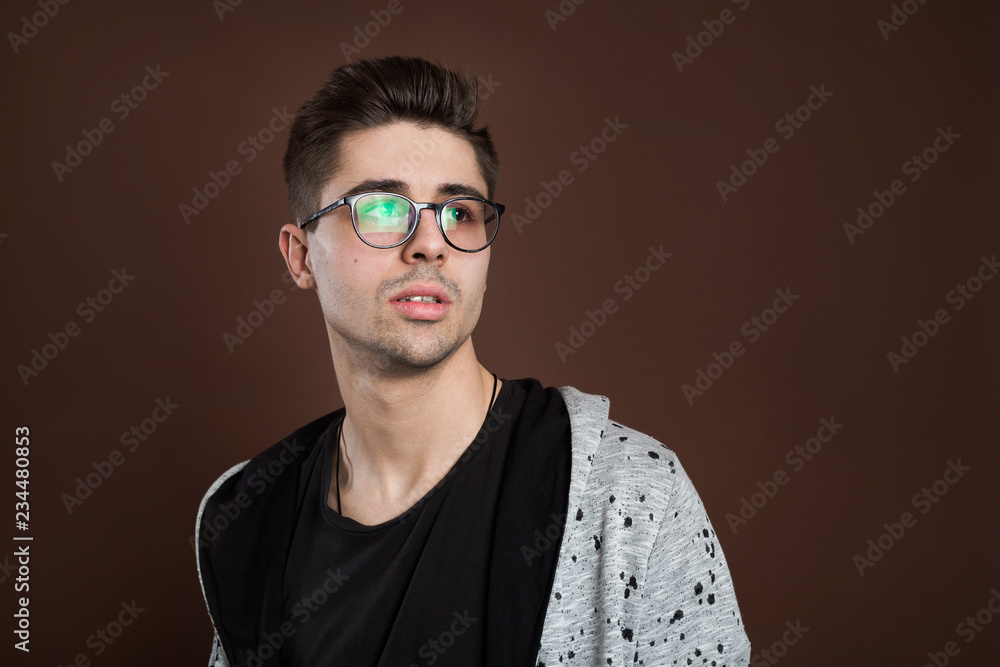 Young man in depression. Stylish male student wears round spectacles, has trendy hairstyle, looks confidently, isolated over brown background. People and human expressions Young man in depression. Stylish male student wears round spectacles, has trendy hairstyle, looks confidently, isolated over brown background. People and human expressions