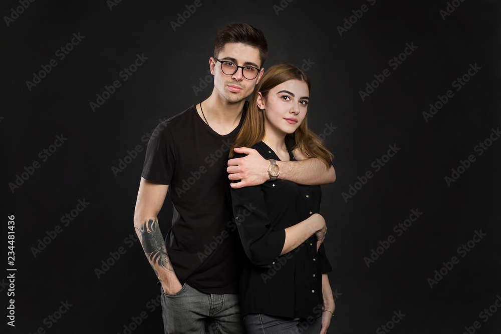 Portrait of young couple in black clothes wearing trendy glasses and posing over black background. Portrait of young couple in black clothes wearing trendy glasses and posing over black background.