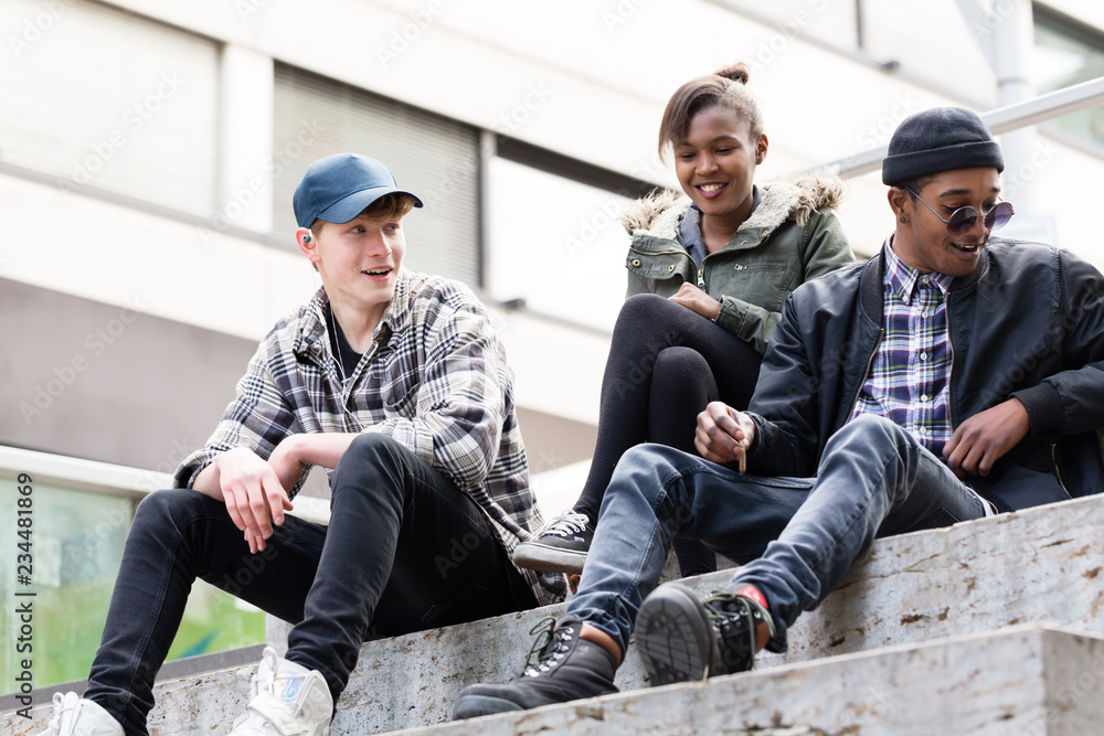 Fototapeta premium Group of young friends sitting on staircase making fun