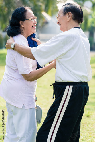 An elderly man using towel to wipe the sweat from his wife's face after exercising