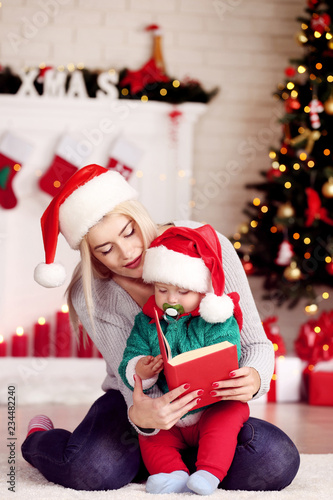 Mother and son in santa hats reading book at home